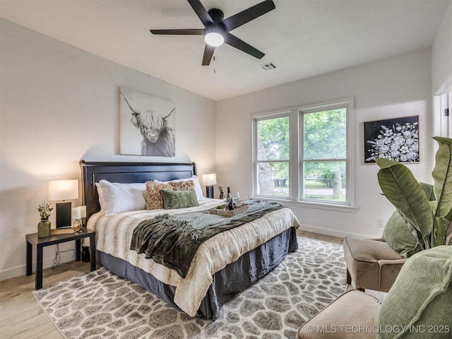 bedroom with baseboards, ceiling fan, wood finished floors, and visible vents