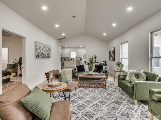 living area with visible vents, plenty of natural light, and vaulted ceiling