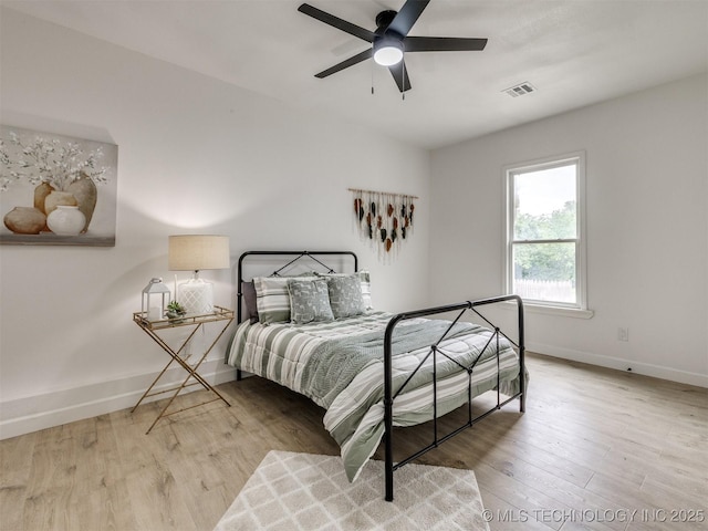 bedroom with baseboards, ceiling fan, wood finished floors, and visible vents