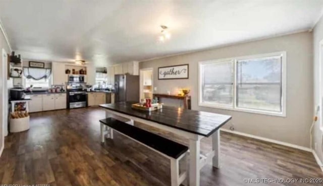 dining room featuring plenty of natural light, dark wood finished floors, and baseboards