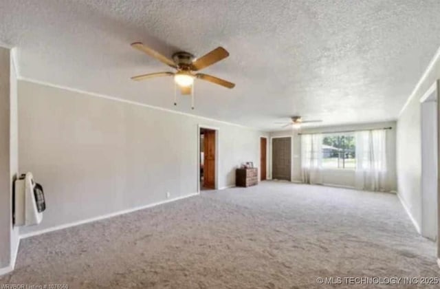 carpeted spare room with baseboards, a ceiling fan, and a textured ceiling