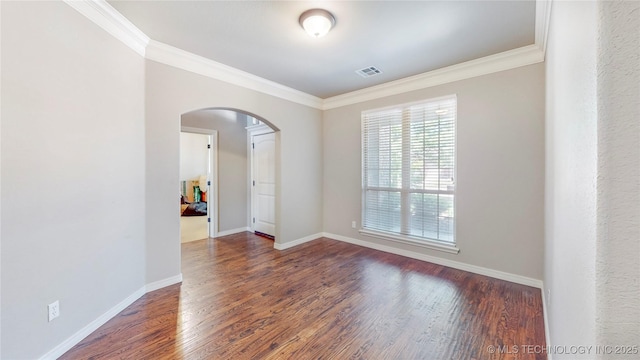 empty room with visible vents, arched walkways, wood finished floors, and ornamental molding