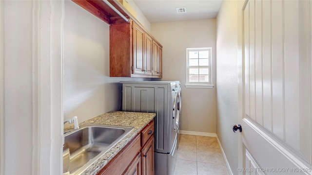 laundry area featuring visible vents, cabinet space, a sink, light tile patterned floors, and washer and dryer