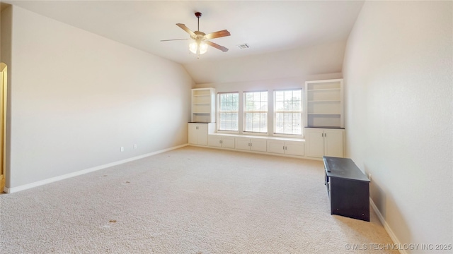 spare room featuring a ceiling fan, light colored carpet, visible vents, vaulted ceiling, and baseboards