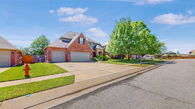 traditional-style home with a garage, a front lawn, fence, brick siding, and driveway