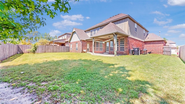 back of house featuring a fenced backyard, a patio, a lawn, and brick siding