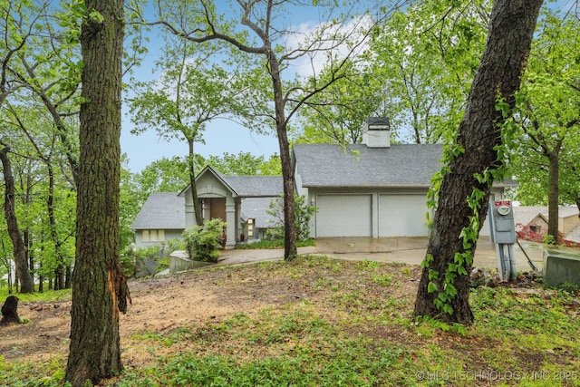 ranch-style home with concrete driveway, an attached garage, a chimney, and a shingled roof