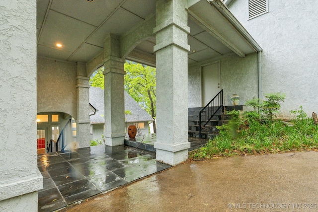 entrance to property featuring a patio, visible vents, and stucco siding