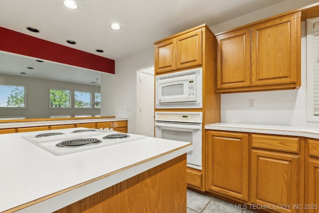 kitchen featuring light countertops, recessed lighting, brown cabinetry, and white appliances