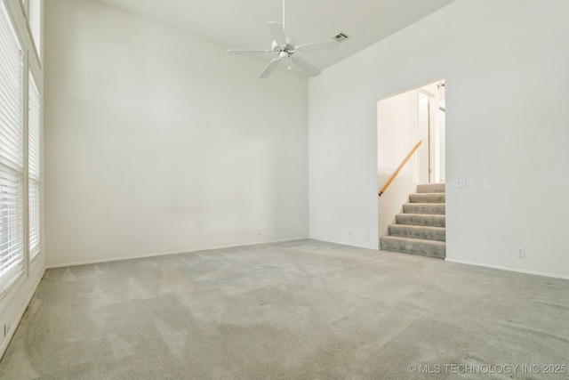 empty room featuring visible vents, carpet, ceiling fan, and stairs