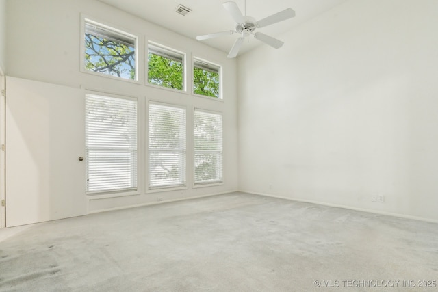 unfurnished room featuring a ceiling fan, a high ceiling, visible vents, and carpet