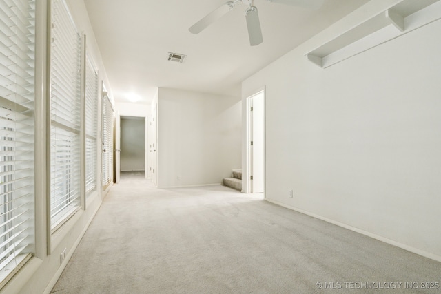 carpeted spare room featuring visible vents, baseboards, and ceiling fan
