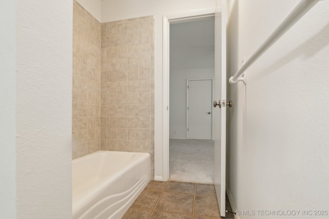 full bathroom featuring tile patterned floors, a textured wall, and bathing tub / shower combination