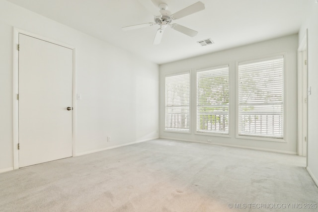 carpeted spare room featuring baseboards, ceiling fan, and visible vents