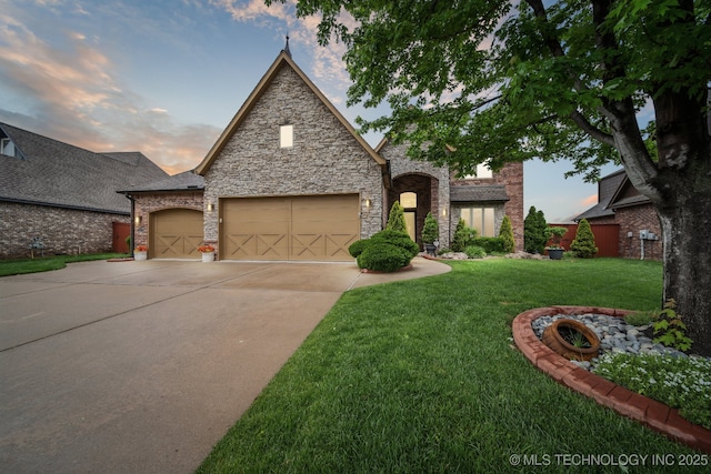 view of front of home featuring a lawn, a garage, driveway, and stone siding