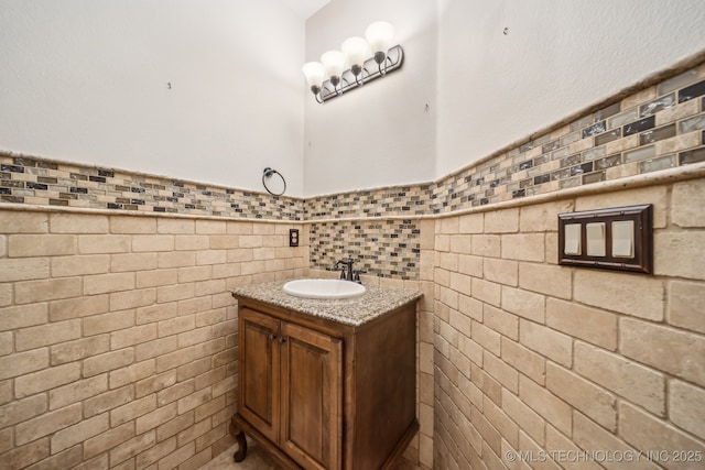 bathroom with vanity, a wainscoted wall, and tile walls