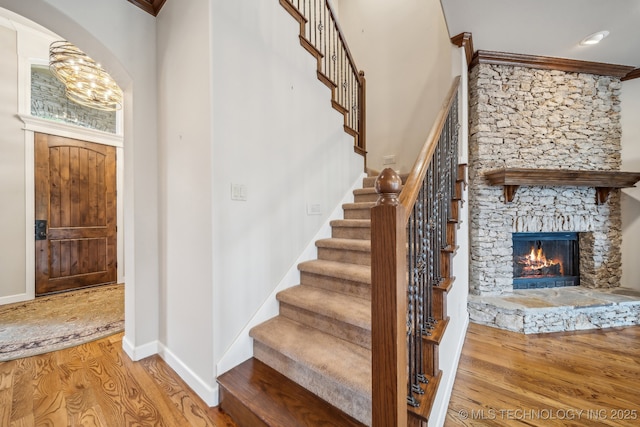 stairway featuring arched walkways, baseboards, wood finished floors, and a fireplace