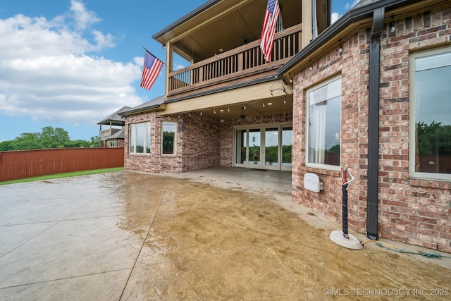 exterior space with a patio, brick siding, fence, and a balcony
