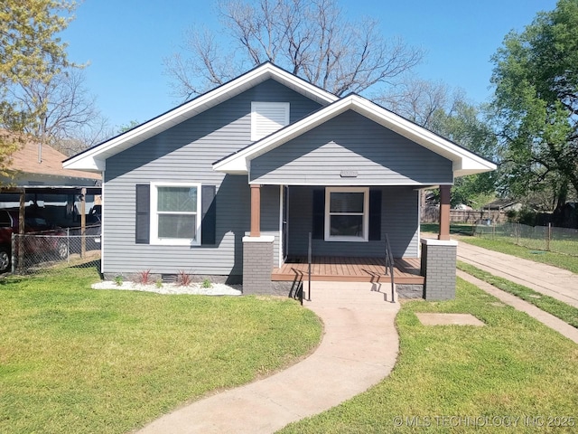 bungalow featuring covered porch, fence, and a front yard