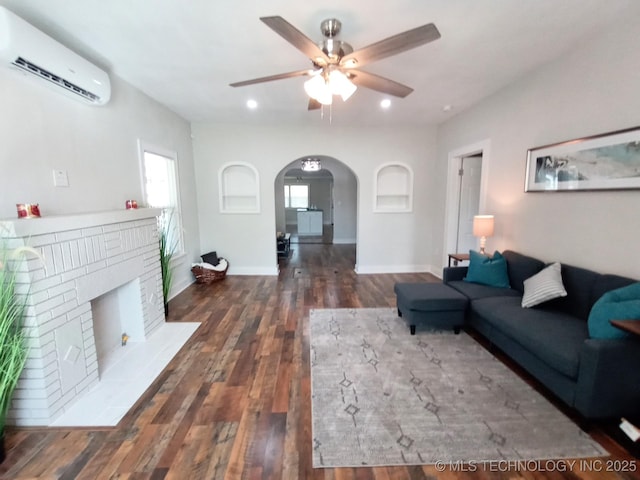 living area featuring a ceiling fan, arched walkways, a wall mounted AC, wood finished floors, and recessed lighting