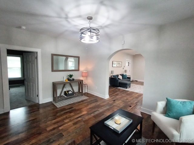 living area with an inviting chandelier, arched walkways, baseboards, and wood finished floors