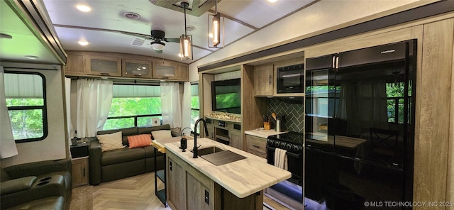 kitchen featuring a ceiling fan, a kitchen bar, visible vents, a sink, and black appliances