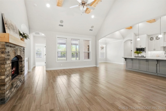 15916 E 106th Pl, Owasso, OK 74055 - unfurnished living room with a fireplace, light wood-type flooring, high vaulted ceiling, and a ceiling fan