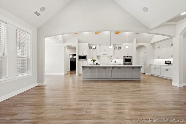 15916 E 106th Pl, Owasso, OK 74055 - kitchen featuring arched walkways, high vaulted ceiling, visible vents, and appliances with stainless steel finishes