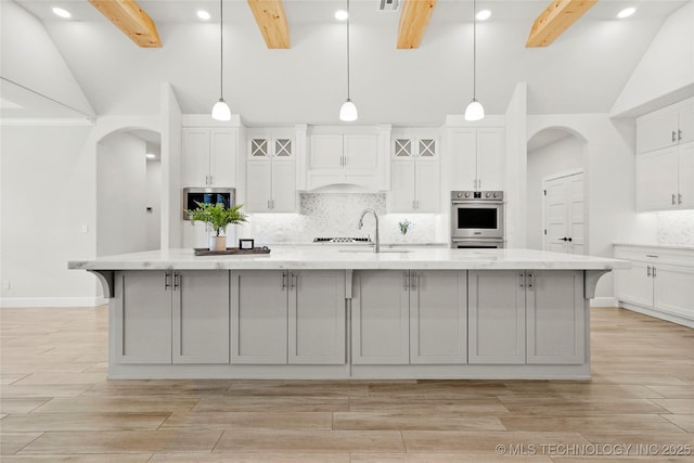 15916 E 106th Pl, Owasso, OK 74055 - kitchen with arched walkways, backsplash, lofted ceiling with beams, and stainless steel microwave