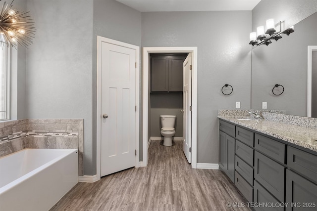 543 Edgewood, Durant, OK 74701 - full bath with vanity, a garden tub, wood finished floors, and baseboards