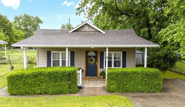 bungalow featuring fence, covered porch, a shingled roof, and a front yard