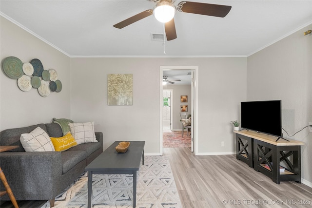 living area featuring ceiling fan, visible vents, crown molding, wood finished floors, and baseboards