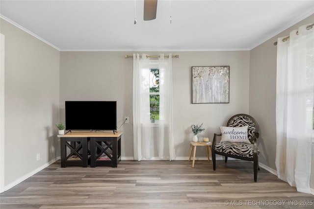 sitting room with crown molding, ceiling fan, baseboards, and wood finished floors