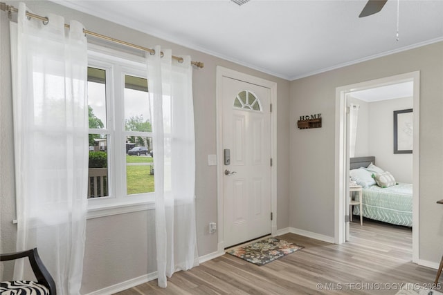 foyer with ornamental molding, ceiling fan, wood finished floors, and a wealth of natural light