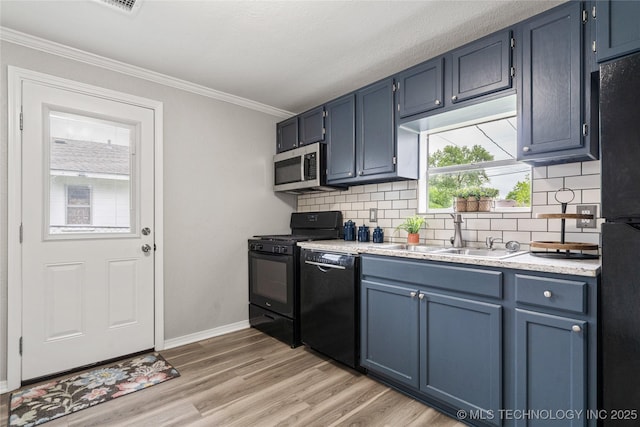 kitchen with backsplash, blue cabinetry, a sink, light countertops, and black appliances