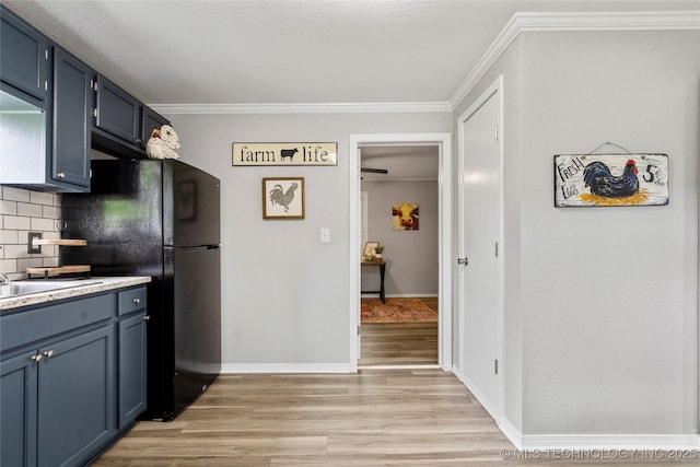 kitchen featuring light wood-style floors, blue cabinetry, freestanding refrigerator, backsplash, and ornamental molding
