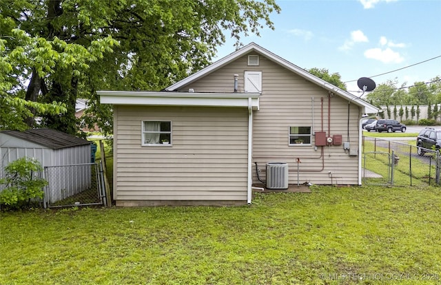back of house featuring fence, central air condition unit, a yard, and a shed