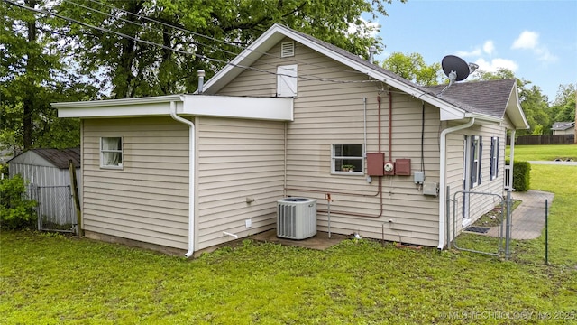 back of property with central AC unit, fence, and a yard