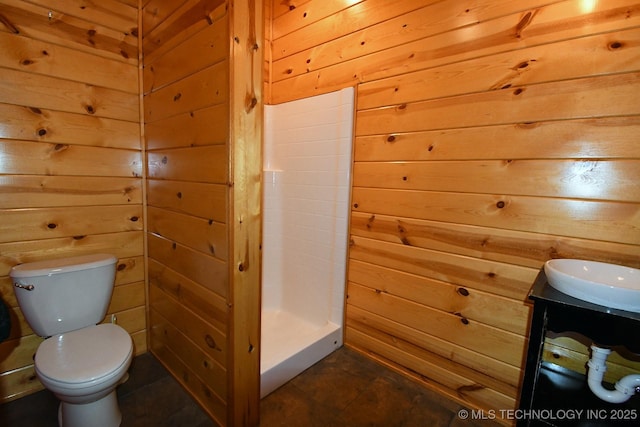 full bathroom featuring wooden walls, toilet, a shower stall, and vanity