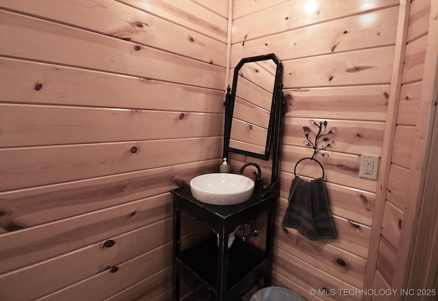 half bathroom featuring vanity and wooden walls
