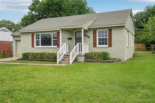 ranch-style home featuring brick siding, a front yard, fence, and roof with shingles