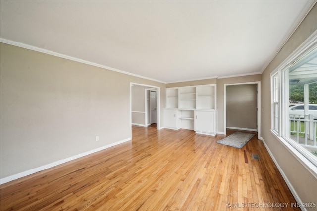 unfurnished bedroom featuring baseboards, light wood finished floors, crown molding, and visible vents
