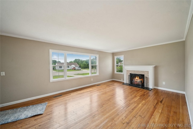 unfurnished living room featuring visible vents, baseboards, ornamental molding, light wood-style flooring, and a premium fireplace