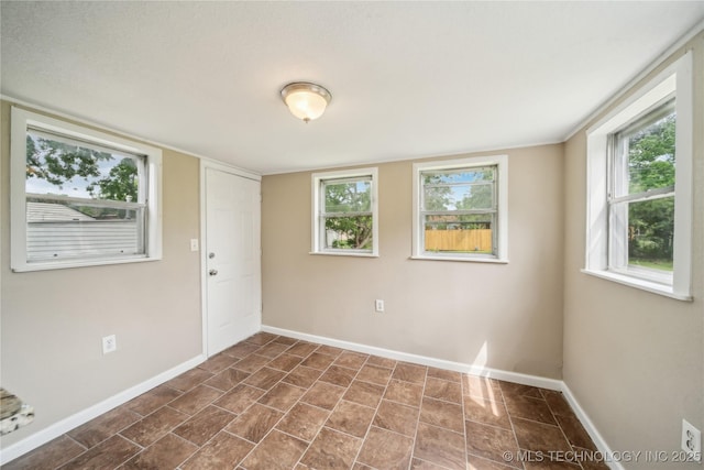 spare room featuring baseboards and dark tile patterned floors