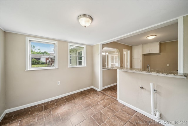 kitchen featuring baseboards, a peninsula, and light stone counters