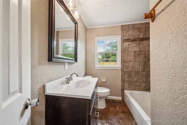 bathroom featuring stone finish flooring, vanity, toilet, ornamental molding, and a textured wall
