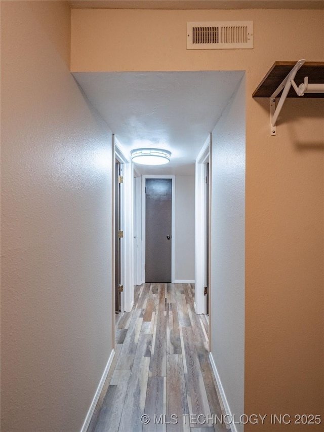 corridor featuring baseboards, visible vents, and light wood-style floors