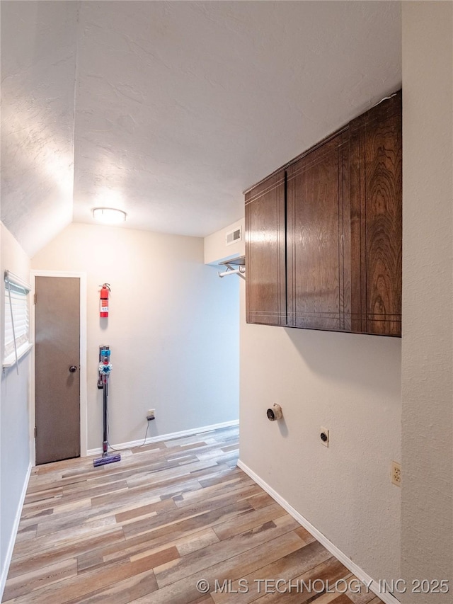 laundry area featuring cabinet space, baseboards, visible vents, and light wood-style flooring
