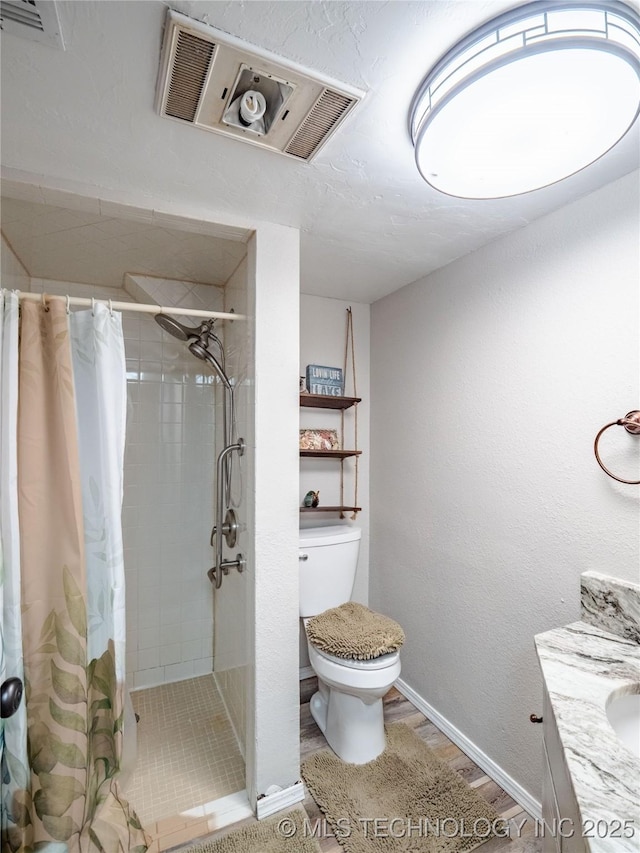 bathroom featuring baseboards, a tile shower, toilet, and vanity