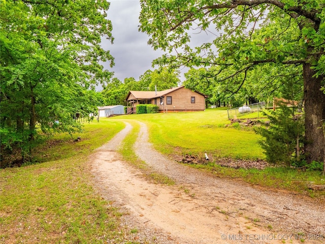 view of front of home with fence, dirt driveway, and a front yard